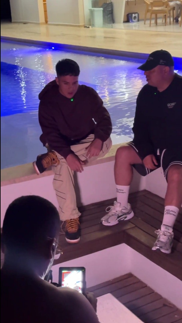 Dos integrantes de Fama i. en sesión de trabajo junto a la piscina mientras una cámara registra la conversación.
